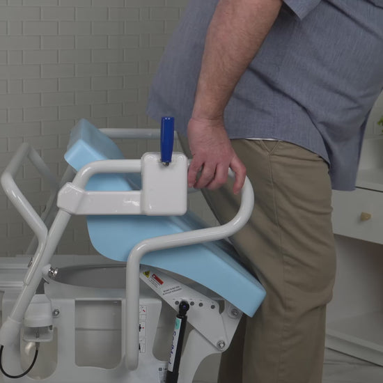 An elderly or disabled user gripping the safety handrails of a SedMed Toilet Lift Assist for standing support