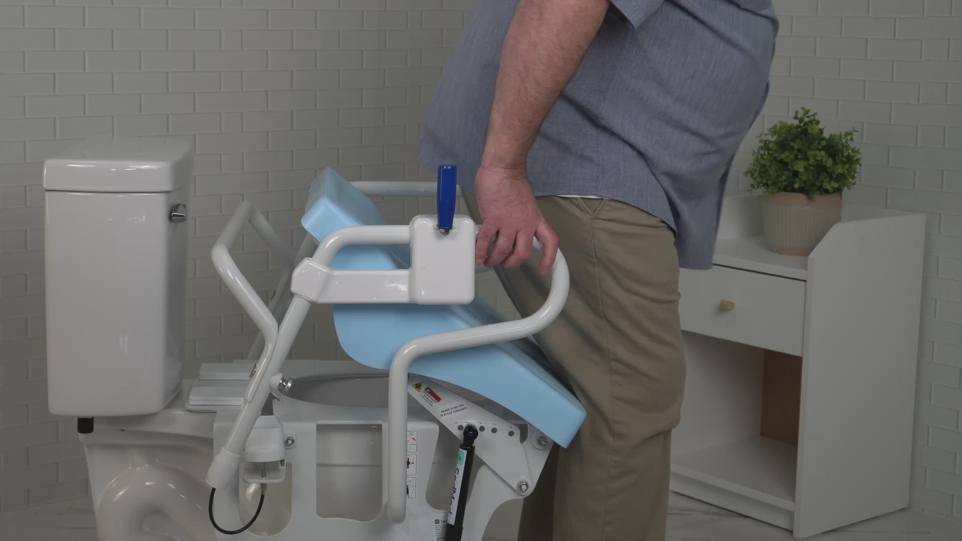 An elderly or disabled user gripping the safety handrails of a SedMed Toilet Lift Assist for standing support
